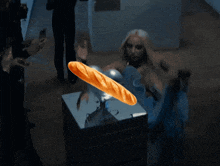 a woman in a blue dress is holding a loaf of bread in her hand