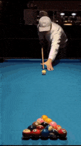 a man in a white hat is playing pool on a blue pool table
