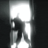 a silhouette of a person walking in a doorway