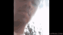 a close up of a person smoking a cigarette with a tree in the background .