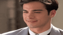 a man in a suit and tie is smiling and looking at the camera