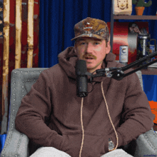 a man sitting in front of a microphone wearing a hat that says harley davidson on it