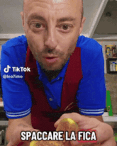 a man in a blue shirt and red vest is holding a piece of food with the words spaccare la fica below him