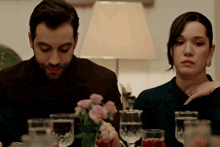 a man and a woman sit at a table with glasses of wine