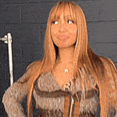 a woman with long blonde hair is wearing a sweater and a necklace with the letter n on it