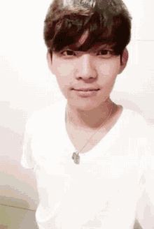a young man wearing a white shirt and a necklace