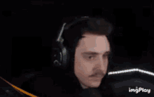 a man wearing headphones is making a funny face while sitting in front of a microphone .