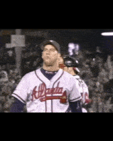 a baseball player wearing an atlanta jersey stands in the outfield