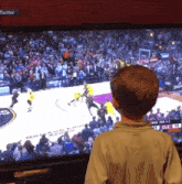 a young boy watches a basketball game on a television with a twitter icon in the corner