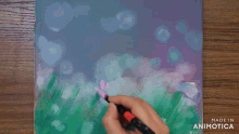 a person is painting a picture on a canvas with the words made in animatica on the bottom right