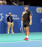 a man holding a tennis racquet on a tennis court in front of a wall that says republica nicana