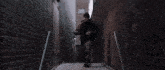 a man standing in a dark alleyway with a brick wall
