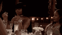 two women are sitting at a table drinking wine .