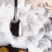 whipped cream is being poured on a cake with a fork