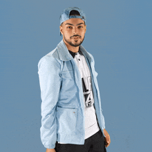 a man wearing a light blue jacket and a white shirt with the letter l on it