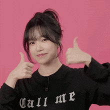 a girl wearing a black shirt that says call me is giving a thumbs up