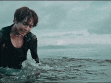 a man in a wet suit is standing in the water .