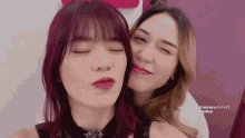 a woman with red hair is kissing another woman on the cheek .