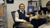 a man with a mustache sits at a desk with a computer screen that says google on it