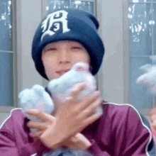 a person wearing a blue beanie is holding a stuffed animal in their hands .