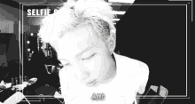 a black and white photo of a young man taking a selfie with the caption ah .