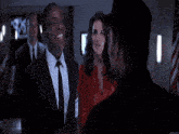 a man in a suit and tie laughs with another man in a hat