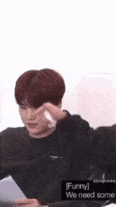 a man with red hair is holding a piece of paper in his hand and wipes his eyes with a tissue .