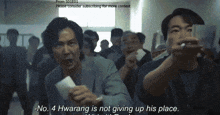 a man in a crowd says " no 4 hwarang is not giving up his place " while holding a piece of paper