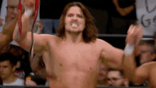 a shirtless wrestler is holding a championship belt in a ring .