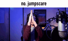 a man sitting in front of a microphone with his hands on his face and the words " no jumpscare " written above him