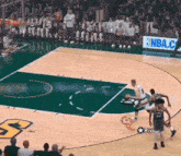 a basketball game is being played on a court with a nba.com banner in the background