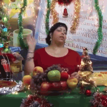 a woman in a red shirt stands in front of a table with fruit and a sign that says ' coca-cola '