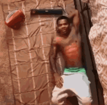 a shirtless man laying on a bed with a basketball on top of him