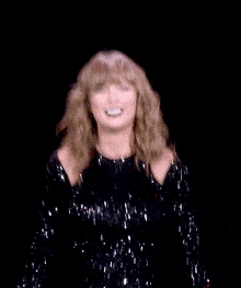 a woman in a black sequined dress is dancing in the dark