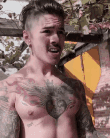 a shirtless man with a heart tattoo on his chest is talking
