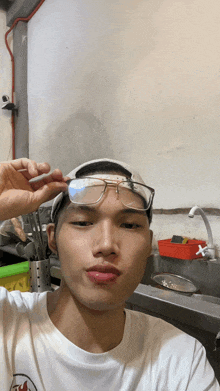 a young man wearing glasses and a baseball cap is taking a picture