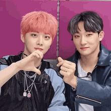 two young men with pink hair are making a heart with their hands
