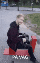 a man is sitting on a red box with the word pa vag written on it