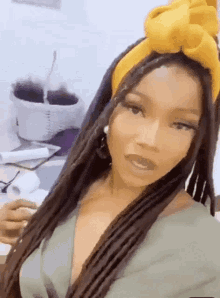 a woman with dreadlocks and a yellow headband is taking a selfie .