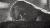a black and white photo of a woman with long hair laying down .