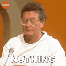 a man with glasses says nothing while sitting in front of a microphone
