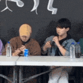 a group of people sitting at a table with bottles of water on it