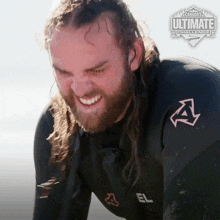 a man in a wetsuit is smiling in front of a canada 's ultimate challenge advertisement
