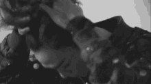 a black and white photo of a young man holding his head .