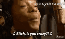 a woman wearing headphones is singing into a microphone and says `` yes ! over yo ass ! ''