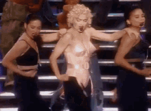 a woman in a bra is dancing on a stage with two other women