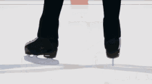 a man is skating on a ice rink in a black suit .