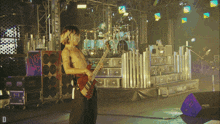 a man playing a guitar on a stage with the letter d in the bottom right corner