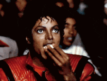 a man in a red jacket is eating something with his mouth open