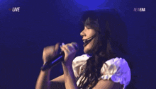 a woman singing into a microphone with the words live on the bottom left